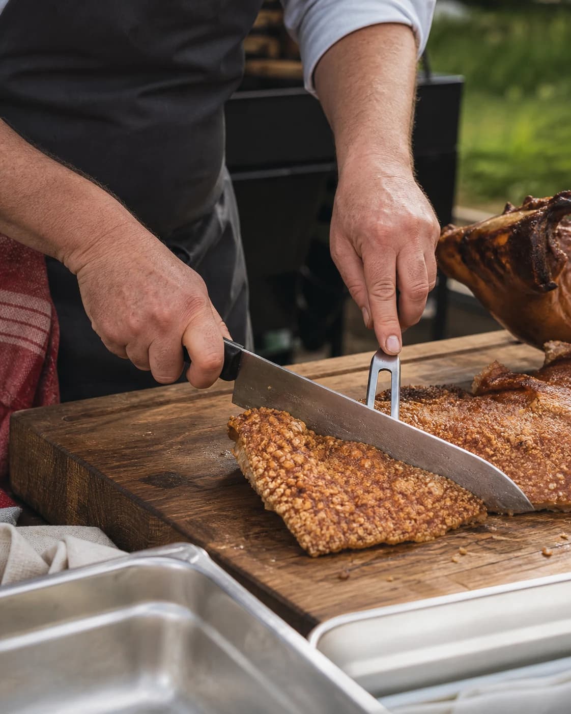 Whole hog being carved by the chef as guests queue at a summer wedding