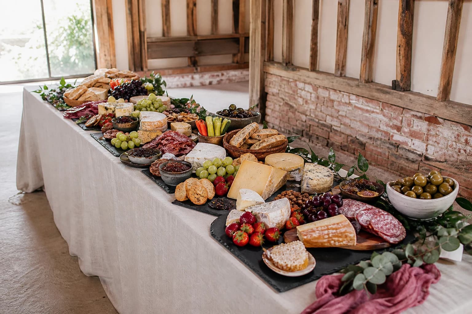 Grazing table styled with charcuterie, cheeses, breads and foliage